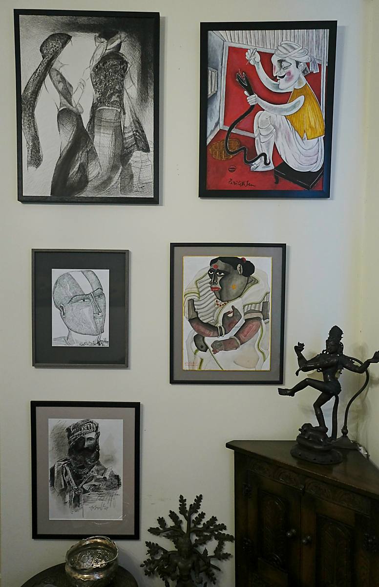 A wall of framed drawings and paintings, with a bronze dancing figure