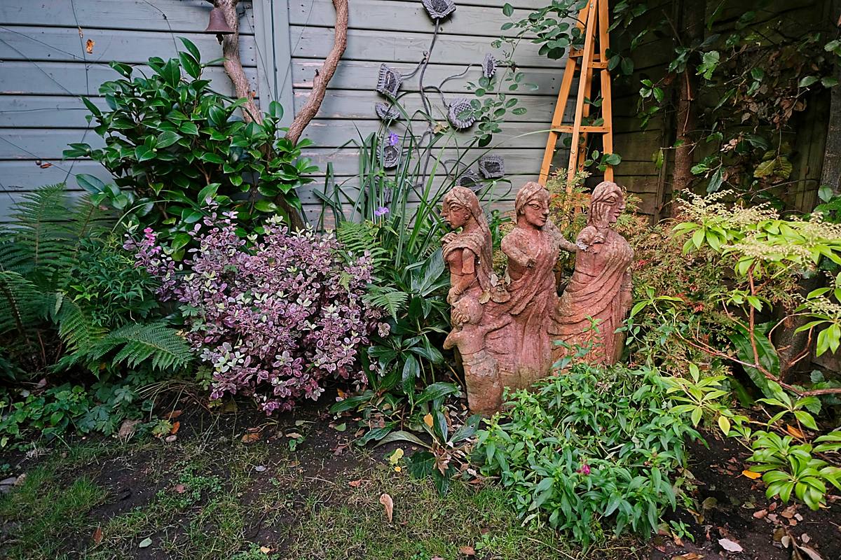 Terracotta figures among planting at the end of the garden