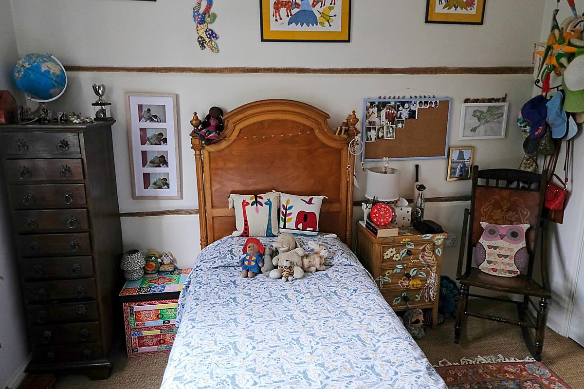 A child’s bedroom with a wooden bed and pictures on the walls